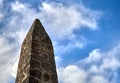 Old stone and mortar obelisk with a cloudy blue sky in the backg Royalty Free Stock Photo