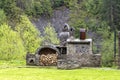 Old stone stove with firewood and smokehouse in the mountains of the Carpathians Royalty Free Stock Photo
