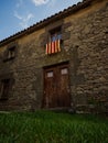 Old stone rock house with red yellow Senyera flag in historic town village of Tavertet Osona Catalonia Spain Pyrenees