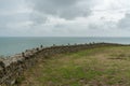 Old stone rock wall and view over an expanisve ocean under an overcast sky Royalty Free Stock Photo