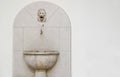 Old stone sink and a small crane with a lion sculpture above it against a white background Royalty Free Stock Photo