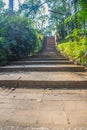 Old stone stair case in the ancient temple with green trees surrounding. Peaceful stone path going uphill in the forest leading up Royalty Free Stock Photo