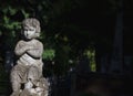 Old stone statue child to which the sun shines on the dark background. Royalty Free Stock Photo