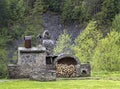 Old stone stove with wood and smokehouse in the mountains Royalty Free Stock Photo