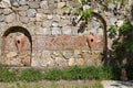 Old stone structure with urns built into a stone wall in the gardens of a restaurant in Turkey