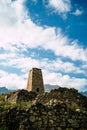 Old stone tower in green mountainous terrain. Ancient stone building of old town located on green hill against mountains Royalty Free Stock Photo