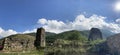 Old stone tower in green mountainous terrain. Ancient stone building of old town located on green hill against mountains Royalty Free Stock Photo