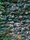 An old stone wall with coarse stones and moss and plants