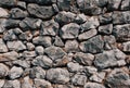 Old stone wall consisting of stacked naturally shaped loose rocks - background pattern