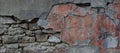 Old stone wall covered with cement. Half of cement on this wall is crumbled. There are cinderblocks under the cement. Panorama. Royalty Free Stock Photo