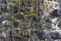 Old stone wall of large cobblestones overgrown with green moss Royalty Free Stock Photo