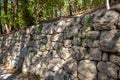 An old stone wall made of rough stone. An ancient fortified wall fence with a pattern of green grass and moss. Royalty Free Stock Photo