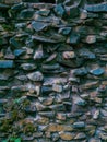 An old stone wall with coarse stones and moss and plants