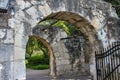 Old stone walls and archways with trees and vines and hanging lanterns and a wrong iron gate