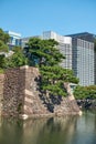 Old stone walls of Edo castle surrounded by moat with modern buildings on background. Tokyo. Japan