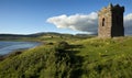 An old stone Watch tower over looking Dingle Bay Co. Kerry Ireland as a fishing boat heads out to sea. Royalty Free Stock Photo