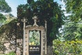 Old stone weathered gate with moss on the wall and metal door in a park.