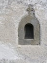 Old stone window with fleur de lys religious motif and grille.