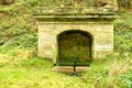 Old stony rural fountain in the forest with fresh crystal clear water. Royalty Free Stock Photo