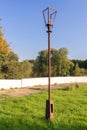 Old street lamp with broken light bulb and torn electrical wires on rusty metal pole in abandoned Park area against background of Royalty Free Stock Photo