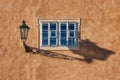 An old street lamp and shadow on a wall with a window Royalty Free Stock Photo