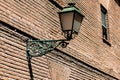 Old street lamp on the wall of the brick building in Alcala de Henares, Spain