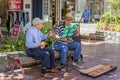Old street musicians sitting on a bench in the streets of Wellington and playing instruments Royalty Free Stock Photo