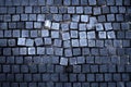 Old street surface: unsettled cobbles, tiles on pothole road color photo for backgrounds. Royalty Free Stock Photo