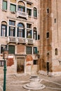 Close-ups of building facades in Venice, Italy. An old street well in the square in front of a brick house. There are Royalty Free Stock Photo