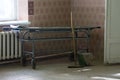 Old stretcher gurney bed in the hospital hallway. Wooden mop bucket and rag. A horrible old hospital or morgue
