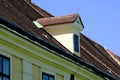 old stucco roof dormer with small wood window. sloped brown clay tile roof with round beaver tail edge. Royalty Free Stock Photo