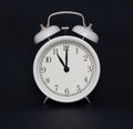 Old-style alarm clock, black and white, it`s eleven o`clock.