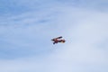 Old style biplane flying out of the clouds to the blue sky Royalty Free Stock Photo