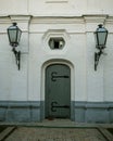 Old-style closed wooden doors in a stone wall which are adorned by hand hammered iron accents and door lanterns. Close-up Royalty Free Stock Photo