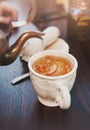 Old-style copper kettle pouring tea to cup on wooden table Royalty Free Stock Photo