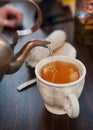 Old-style copper kettle pouring tea to white cup Royalty Free Stock Photo