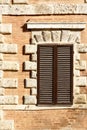 European window with brown wood shutters in an interesting brick and stone wall Royalty Free Stock Photo