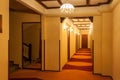 Old style hotel hallway with wooden brown doors, reddish carpet, and yellow walls. Mirror seen near the floor stairs Royalty Free Stock Photo