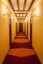 Old style hotel hallway with wooden brown doors, reddish carpet, and yellow walls Royalty Free Stock Photo