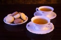 Old-style kettle with two cups of tea with cookies on black Royalty Free Stock Photo