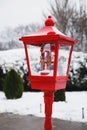 An old style red lantern with Christmas merry-go-round musical box decoration in it in a snow-covered winter park. Snowy winter. Royalty Free Stock Photo