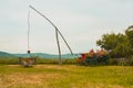 Old style water well with wooden rod and a string. Visible well, bucket and other ornaments on a sunny day