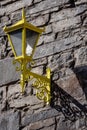 Old style yellow lantern on a stone wall in old town casting strong shadow. Vertical image. Retro theme design. Blacksmith craft