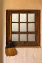 Old styled broom stick hanging by the wooden vintage window to k