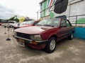 Old stylish red burgundy 1980s Peugeot 505 sedan. Industrial background. Classic car show