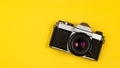 Old stylish vintage camera flat lay on yellow background with copy space. Leather and metal rangefinder retro camera with film, Royalty Free Stock Photo