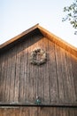 Old stylish wooden barn on the sky background. Rustic wooden barn with wooden roof, dry wreath from wild flowers and Royalty Free Stock Photo