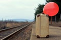 Old suitcase with a red balloon at the train station with retro effect Royalty Free Stock Photo