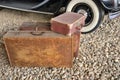 Old suitcases on rubble next to side wheels of vintage car