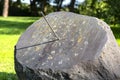 An old sundial made of a large stone with a metal rod, the clock will start at 4 PM.